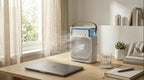 Portable air conditioner on a desk with a laptop, glass of water, and notebook in a bright room.