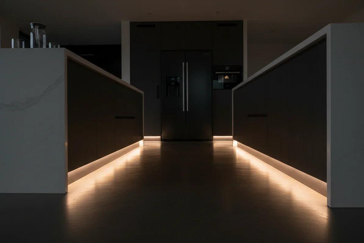 Modern kitchen with dark cabinets and a central island illuminated by subtle lighting using the Smart Motion Sensor Night Lights